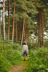 A girl in a poncho and a hat in forest