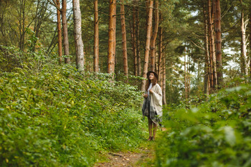 A girl in a poncho and a hat in forest