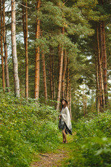 A girl in a poncho and a hat in forest