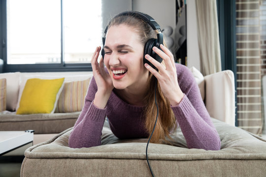 laughing beautiful teenage girl with headphones listening to fun music
