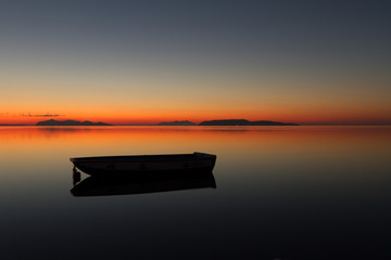 A warm sunset on a calm water, with Islands in the background - obrazy, fototapety, plakaty
