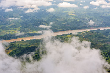 High angle view of Mekong River is the border between Thailand and Laos and farmland along the river looking through the clouds from Doi Pha Tang view point in Chiang Rai Province, Thailand