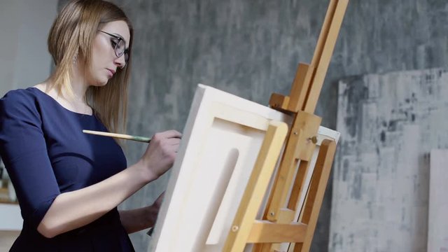 Young attractive woman holding pallette of collors and painting at her home