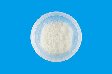Cooked milk protein cocktail in the shaker bottle on blue background, sports nutrition after training, top view