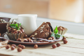 Piece of chocolate cake, mint leaves, hazelnuts and jar with milk