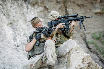 Army sniper during the military operation in the mountain. war, army, technology and people concept.