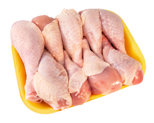 Chicken legs in the yellow tray on the light background