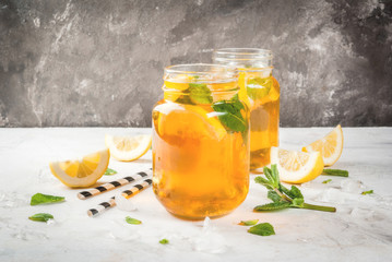 Chilled summer tea with ice, mint and lemon. Two portions in Mason Jars on a white stone table. Copy space