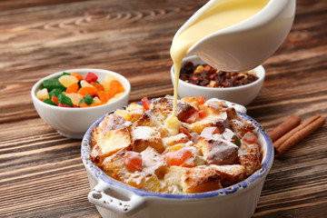 Pouring custard on freshly baked bread pudding in casserole dish