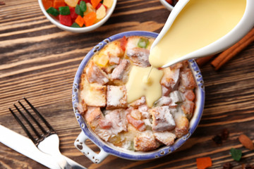 Pouring custard on freshly baked bread pudding in casserole dish