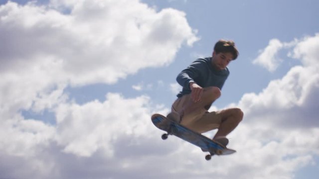 Skateboarder grabs his board in mid air during a jump, in slow motion