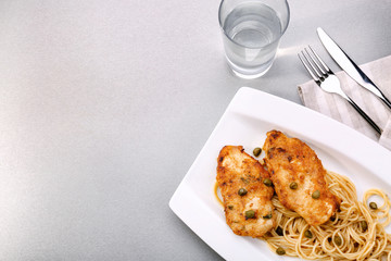 Plate with delicious Italian chicken piccata on table