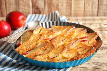 Tasty bread pudding with apples in baking dish on kitchen table