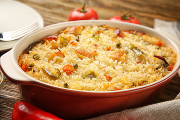 Tasty rice with chicken and vegetables in baking dish on kitchen table