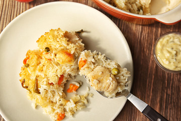 Spoon with tasty rice and plate on background