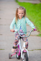 Fototapeta na wymiar Adorable girl riding a bike at beautiful summer day outdoors