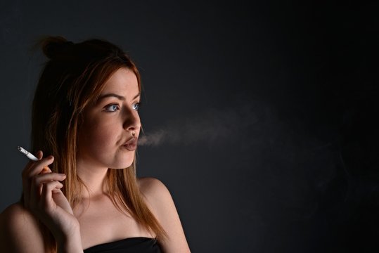 young woman with cigarette, smoking concept on black background