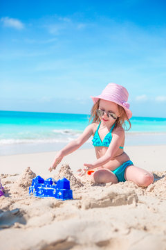 Adorable little girl playing with beach toys on white sandy beach