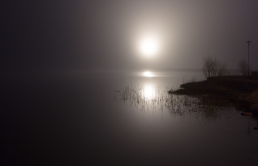 Night lake with a light on the pier.