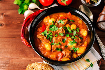 Goulash in ceramic bowl on wooden background. Traditional hungarian soup.