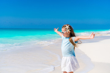 Fototapeta na wymiar Adorable little girl walking along white sand Caribbean beach