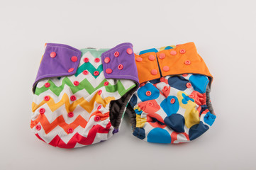 Two colorful baby panties with pattern and buttons lay on white background