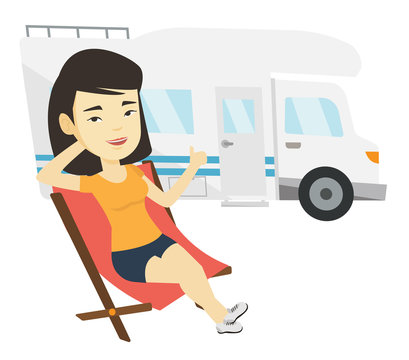 Woman sitting in chair in front of camper van.