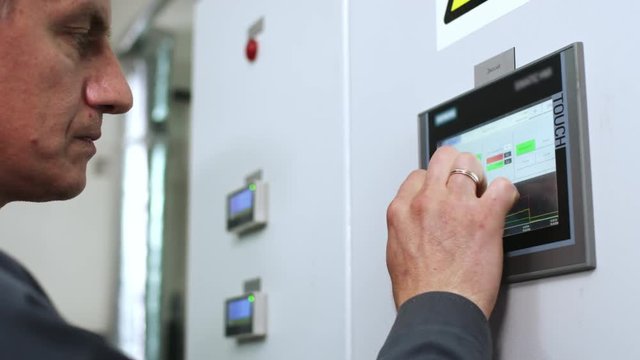 Factory worker touch screen display. Engineer working with industrial computer equipment. Industrial control screen. Close up of control panel screen. Factory man hands touch control monitor