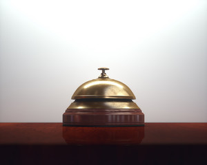 Vintage golden bell on the wooden table of the lobby service.