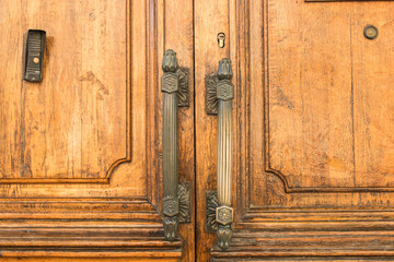 Fototapeta na wymiar Massive wooden doors with large metal handles on the old building close.