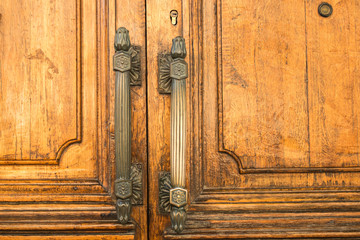 Massive wooden doors with big metal handles on the old building close.