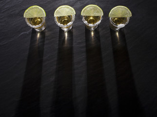 Tequila shots with deep long shadows on black background