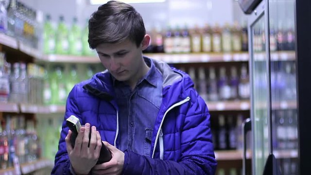 Young attractive man choosing wine in the shop