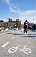 Rowerzysta z dzieckiem jadący po drodze rowerowej. Szwecja, Stockholm. - obrazy, fototapety, plakaty