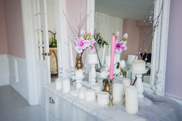 Interior design of white room with beautiful flowers on the served table. Big creative classical mirror at the background.