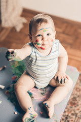 Portrait of a cheerful grimy kid. playing with paint