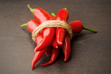 bunch fresh raw red hot chilli pepper on a wooden background tied with a rope