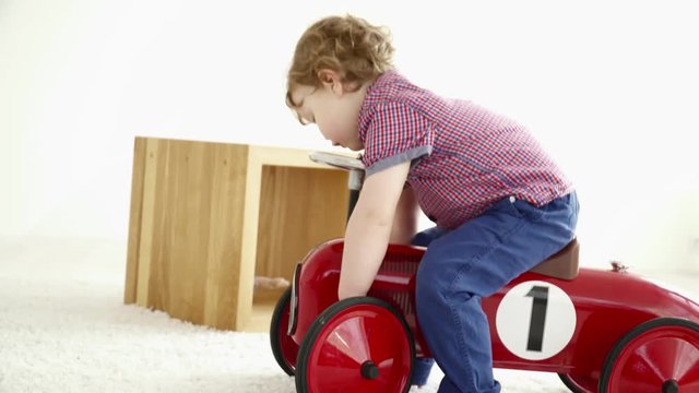 Small boy driving a toy car closeup