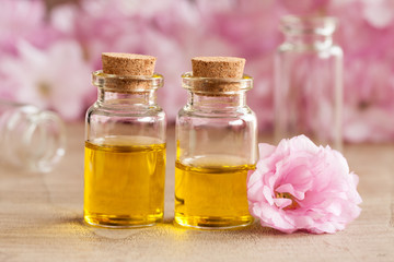 Two bottles of essential oil with pink japanese cherry blossoms in the background