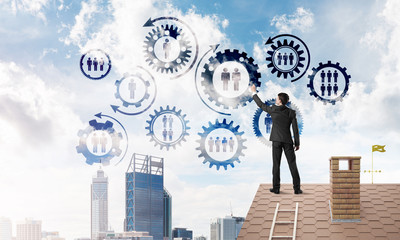 Businessman on house roof presenting teamwork and connection concept. Mixed media