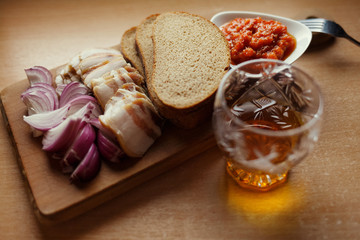 Slised lard, bread, red onion, catsup and glass of alcohol