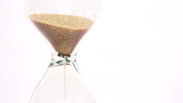 Close-up View of Sand Flowing Through an Hourglass on white background. 4K