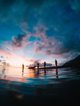 Silhouette of small group of people by waters edge at sunset, Tahiti, South Pacific 