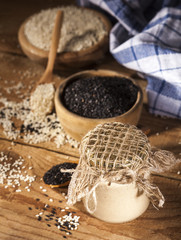 Fresh homemade sesame tahini in a glass jar and seeds in wooden bowls and spoons