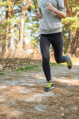 A girl in tights and a hoodie is running by nature. Sports lifestyle