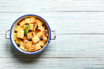 Bowl with delicious bread pudding on wooden table