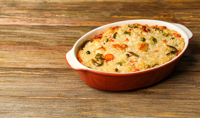 Baking dish with delicious rice and chicken on wooden table