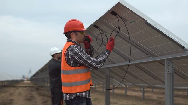 Two worker, the engineer connect cables of solar batteries
