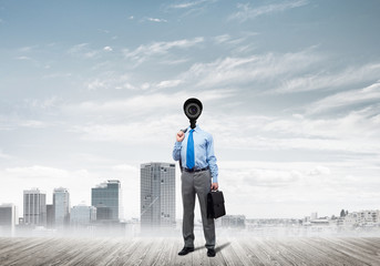 Camera headed man standing on wooden floor against modern cityscape