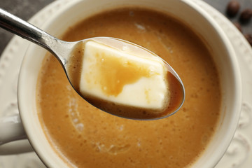 Cup of tasty butter coffee and spoon, closeup